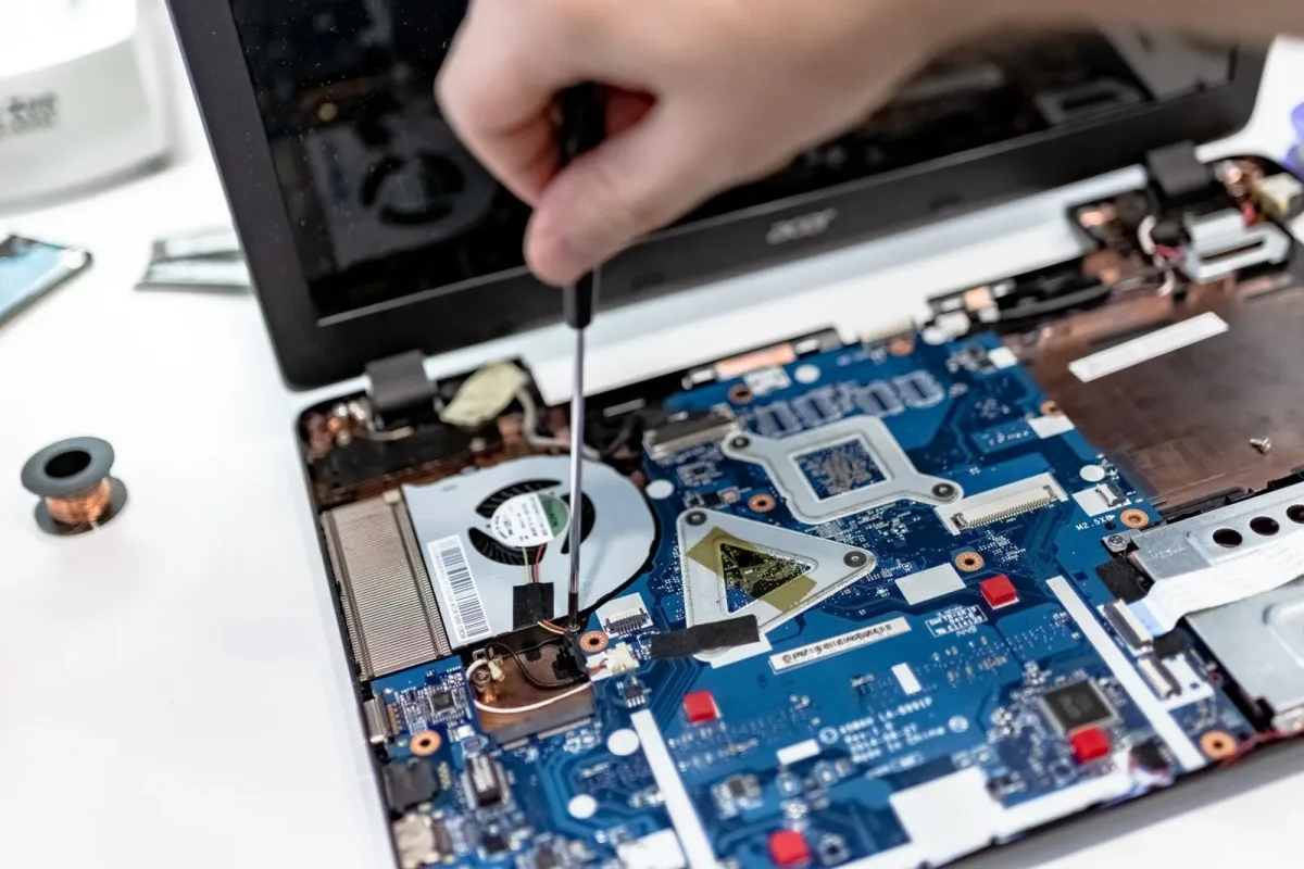 Serwisant ze śrubokrętem naprawiający płytę główną laptopa w trybie pogotowia